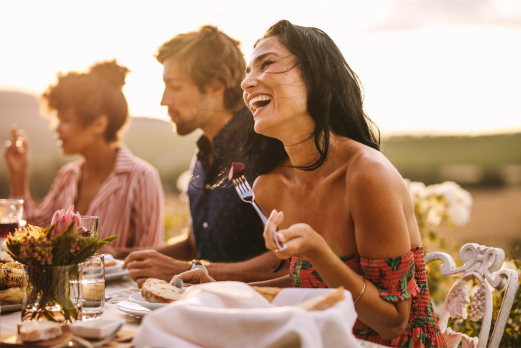 Photo of a woman laughing with friends at an outdoor 25th birthday dinner party